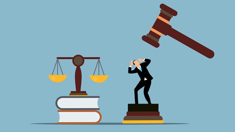 Defendant cowering under judge’s gavel beside scales of justice