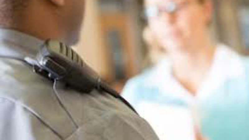 Police officer with shoulder radio interviewing a woman — Colorado domestic-violence response